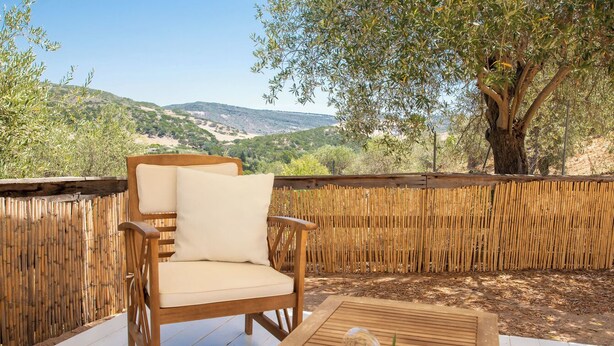A wooden deck with a wicker chair and a table, overlooking a mountainous landscape. - Casa Valverde, Alghero (Alghero)