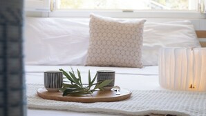 A bed with white bedding and a patterned pillow, a tray with two cups and a spoon, and a lit candle on a bedside table. - Casa Valverde, Alghero (Alghero)