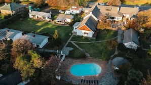 An aerial view of a residential area with houses, a swimming pool, and a well-maintained lawn. - Premier Hotel Himeville Arms (Himeville)