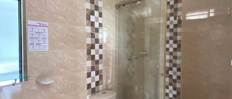 A bathroom with a toilet, bidet, and glass shower enclosure.