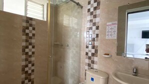 Un baño con cabina de ducha de vidrio, inodoro, lavabo y espejo.