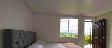 A bedroom with a bed, a window, and a door.