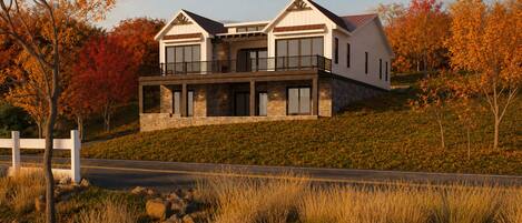 A modern two-story house with a stone facade, large windows, and a balcony.