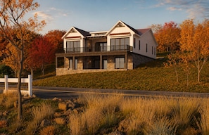 Ein modernes, zweistöckiges Haus mit Naturstein-Fassade, großen Fenstern und einem Balkon.