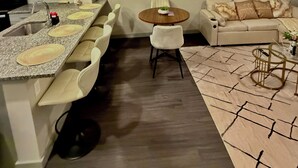 Una cocina moderna con encimeras de granito, horno empotrado y comedor con una mesa redonda y sillas.