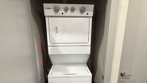 Un lavadero pequeño con lavadora y secadora Whirlpool, una puerta con picaporte y suelo de madera.