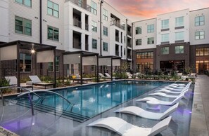 Een modern hotel met een zwembad, ligbedden en een overdekt terras.