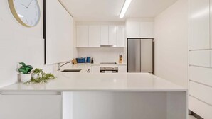 Una cocina moderna con armarios blancos, un refrigerador de acero inoxidable y un reloj en la pared.