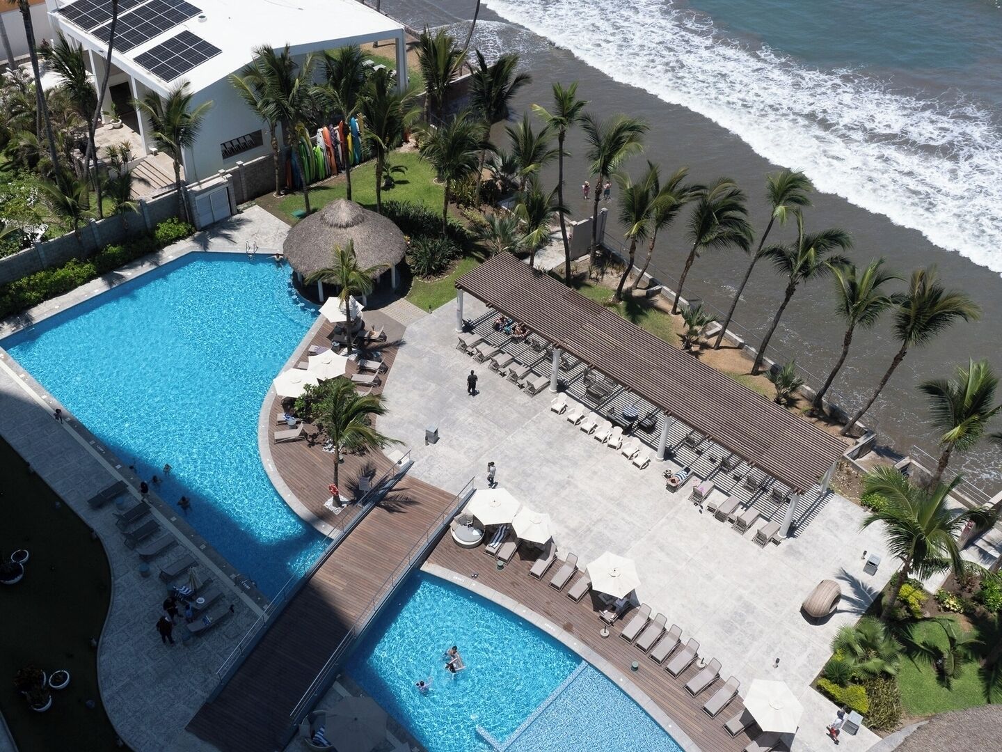A resort with a large pool, lounge areas, and a beach view.