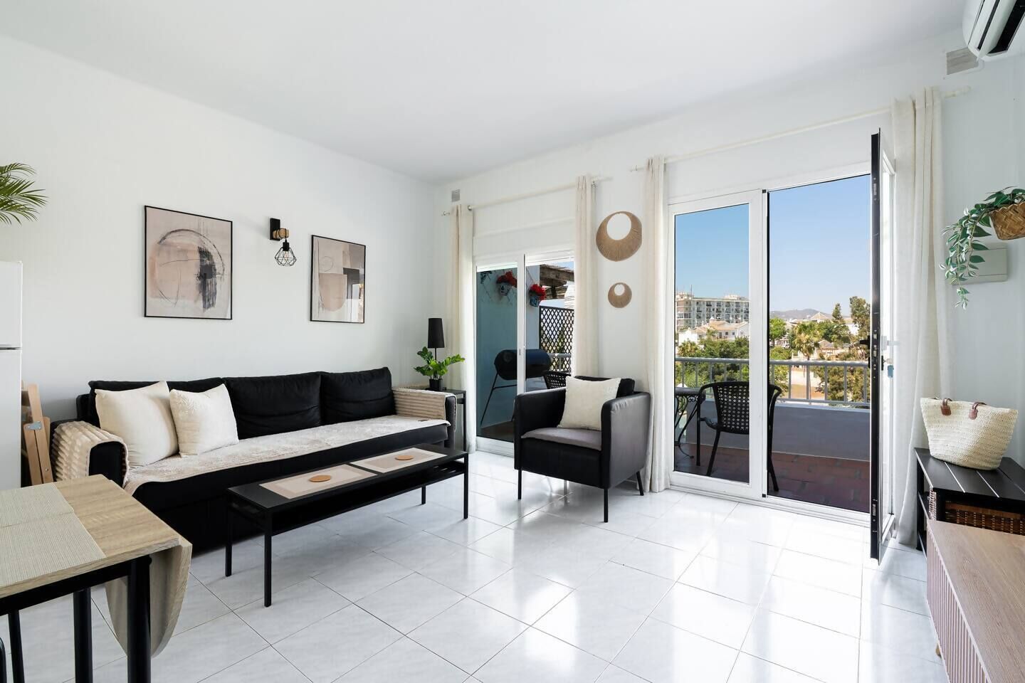 Ein modernes Wohnzimmer mit einer Couch, einem Couchtisch und einem Balkon mit Gartenmöbeln.