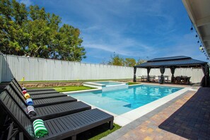 A backyard with a swimming pool, lounge chairs, a barbecue area, and a covered seating area. - Ultimate 8BR Hangout w/ Arcade & Pool Table for 16 (North Las Vegas)