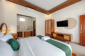 Una camera d'albergo con un letto, una televisione, un armadio in legno, un tavolino con una lampada e una finestra.