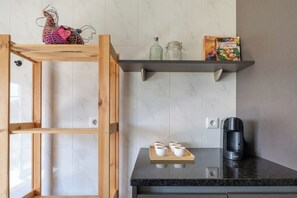 Eine Küche mit einer Holzleiter, einer Kaffeemaschine und einem Regal mit Küchenutensilien.