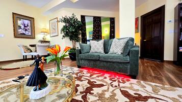 A living room with a sofa, a glass coffee table, a potted plant, and a decorative figurine.