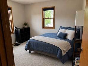 A bedroom with a bed, a window, a bookshelf, and a radiator. - Cozy 3-bedroom house in charming Cedar Falls (Cedar Falls)