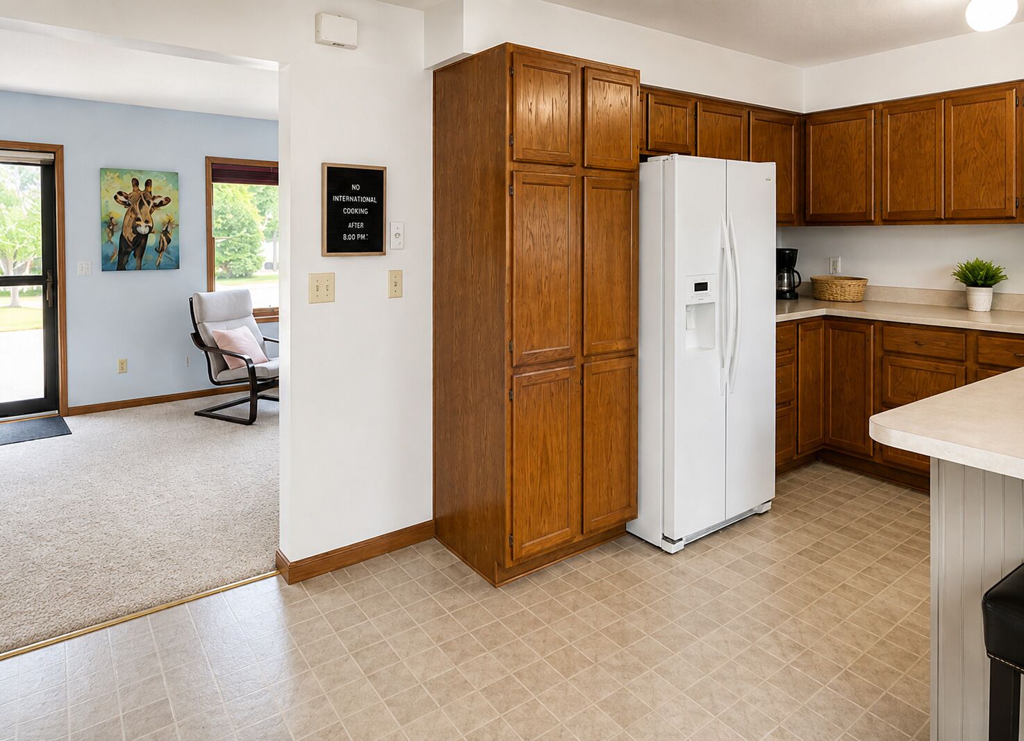 A kitchen with wooden cabinets, a white refrigerator, and a tiled floor.