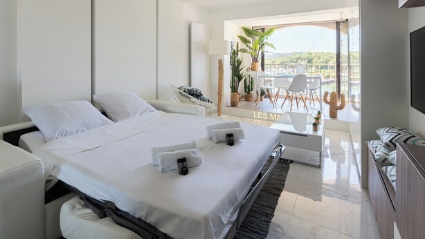 A modern hotel room with a large bed, a balcony with a dining area, and a TV. - Escapade des Marines - Welkeys (Cogolin)