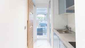 A modern kitchen with a sink, cabinets, and a view through a glass door. - Escapade des Marines - Welkeys (Cogolin)