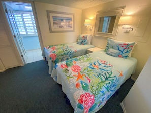 A room with two beds, each with a floral bedspread, a framed picture on the wall, and a mirror above the beds. - Sanibel Harbour Resort: Bay View Tower 137 Waterfront condo with private beach (Fort Myers)