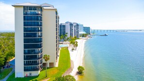 A coastal hotel with multiple high-rise buildings, a beachfront, and a bridge in the background. - Sanibel Harbour 517: Luxury Water View! Experience gorgeous corner view! (Fort Myers)