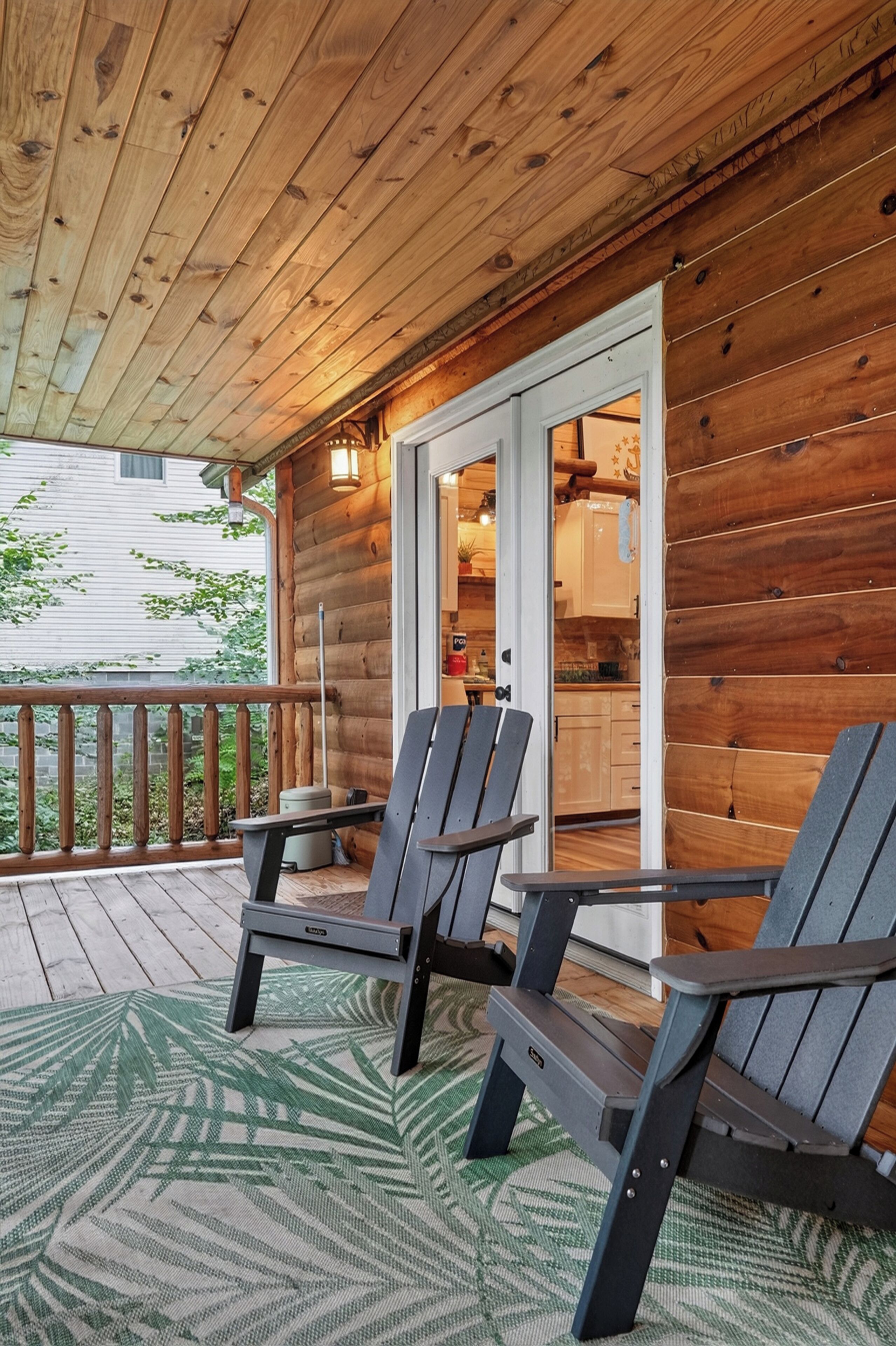 Un terrazzo in legno con poltrone Adirondack e vista su una cucina tramite una porta in vetro.