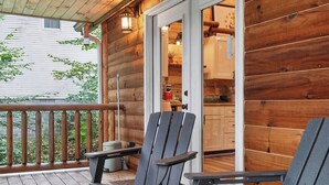 Puinen terassi, jossa on Adirondack-tyyliset tuolit ja lasiovesta avautuva näkymä keittiöön.