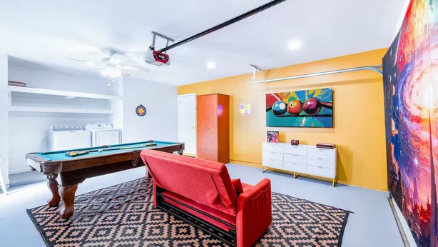 A pool table with a red sofa, a large painting, and a white cabinet in a room with yellow walls. - Blue Haven Villa /Pool, Hot Tub,Mini Golf & Game Room/ Sleeps 12 (Cape Coral)