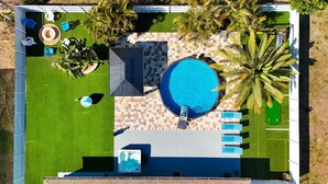 A rooftop pool area with a hot tub, lounge chairs, and palm trees. - Blue Haven Villa /Pool, Hot Tub,Mini Golf & Game Room/ Sleeps 12 (Cape Coral)