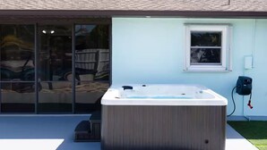 A hot tub outside a house with a sliding glass door, a window, and a power outlet. - Blue Haven Villa /Pool, Hot Tub,Mini Golf & Game Room/ Sleeps 12 (Cape Coral)