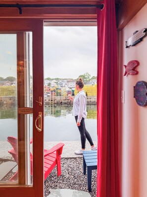 A woman standing at a door with a sign that reads 'PLEASE WATCH YOUR STEP.' - Waterfront Retreat at Motif Annex (Rockport)