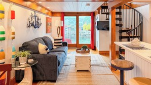 Una sala de estar acogedora con un sofá, una mesita, un televisor y una escalera.