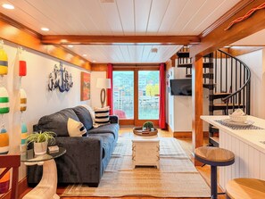 A cozy living room with a sofa, a small table, a TV, and a staircase. - Waterfront Retreat at Motif Annex (Rockport)