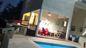 Un edificio su due piani con piscina, area salotto esterna e una cucina a vista.