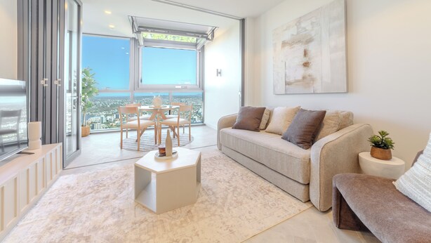 A modern living room with a sofa, a coffee table, and a dining area with chairs and a table. - Sunrise Views on Level 57 | Queen's Wharf King Suite | Pool, Sauna & Parking (Brisbane City)