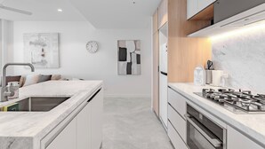 A modern kitchen with a marble countertop, stainless steel appliances, and minimalist decor. - Sunrise Views on Level 57 | Queen's Wharf King Suite | Pool, Sauna & Parking (Brisbane City)