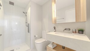 A modern bathroom with a glass shower enclosure, a white toilet, a wooden vanity with a sink, and a mirror above the vanity. - Sunrise Views on Level 57 | Queen's Wharf King Suite | Pool, Sauna & Parking (Brisbane City)