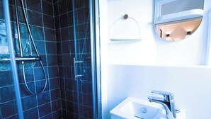 Une salle de bain avec une douche à parois de verre, un lavabo blanc et un miroir avec éclairage intégré.