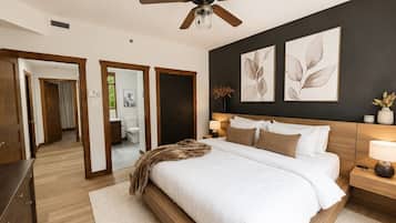 Une chambre à coucher avec un lit, un ventilateur de plafond, une table de chevet et des œuvres d’art accrochées au mur.