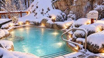 Una piscina cubierta de nieve con una terraza de madera y un cartel.