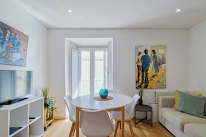 A modern living room with a dining area, a sofa, a TV, and artwork on the walls. - Blue Coconut Second, By Home Match (Setúbal)