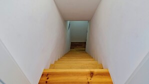 A narrow, wooden staircase leading to a room with white walls and a wooden floor. - Blue Coconut Second, By Home Match (Setúbal)