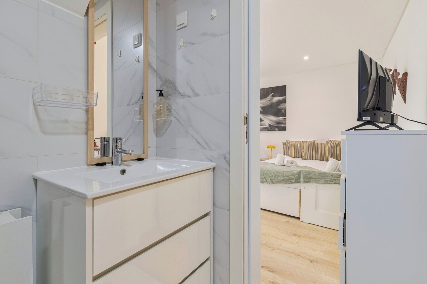 A modern bathroom with a marble sink, a mirror, and a shower area.