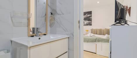 A modern bathroom with a marble sink, a mirror, and a shower area.