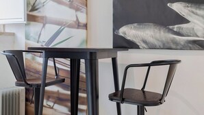 A modern dining area with a black table and chairs, a radiator, and a wall with a large painting of dolphins. - Blue Coconut RC 188, By Home Match (Setúbal)