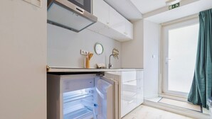A compact kitchen with a built-in refrigerator, a microwave, and a small countertop. - Blue Coconut RC 188, By Home Match (Setúbal)