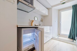 Eine kompakte Küche mit integriertem Kühlschrank, einer Mikrowelle und einer kleinen Arbeitsplatte.
