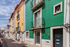 A row of colorful buildings with balconies, a street, and a parked car. - Blue Coconut RC 188, By Home Match (Setúbal)