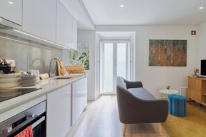 Eine moderne Küche mit Einbauofen und einer Essecke, inklusive Sofa und kleinem Tisch.