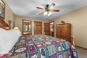 A bedroom with a bed, a ceiling fan, wooden doors, and a cabinet. - Peaceful Retreat Mins to Silver Dollar City&Table Rock Lake_Free Attraction Tickets_Cmty Pools (Branson)