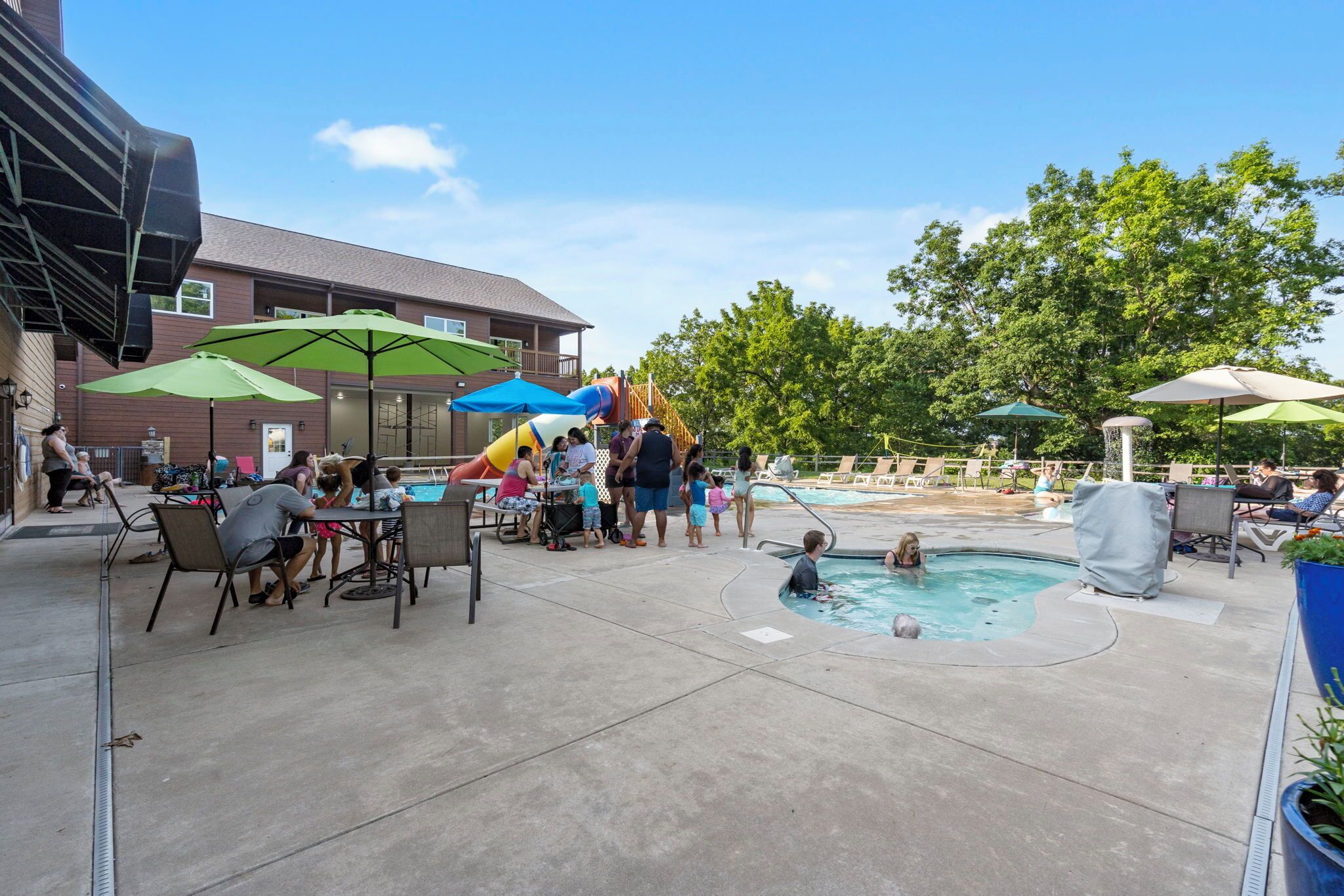 An outdoor pool area with umbrellas, a slide, and lounge chairs.